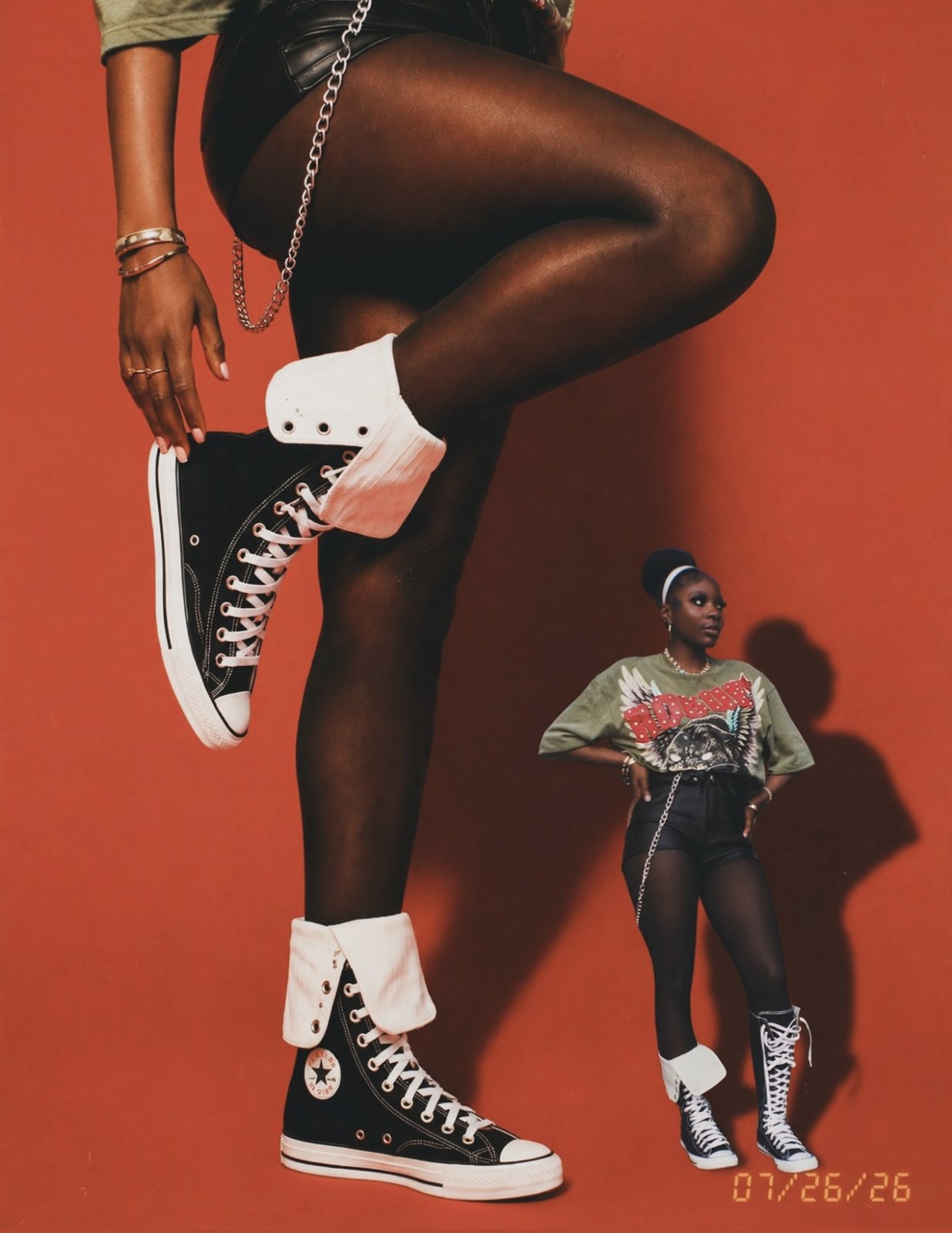 Outfit shoot on an orange backdrop featuring high-top Converse sneakers